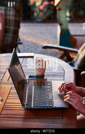 Woman working at home, using portable computer, sitting on patio on summer day Stock Photo