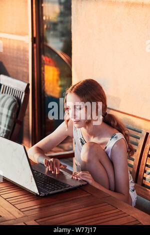 Woman working at home, using portable computer, sitting on patio on summer day Stock Photo
