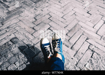 Foot and legs seen from above on a brick, rustic background. Selfie of sneakers on the floor great for any use. Stock Photo