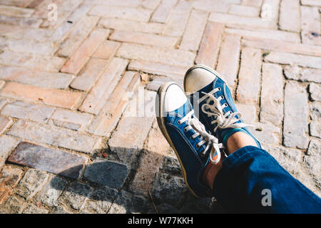 Foot and legs seen from above on a brick, rustic background. Selfie of sneakers on the floor great for any use. Stock Photo
