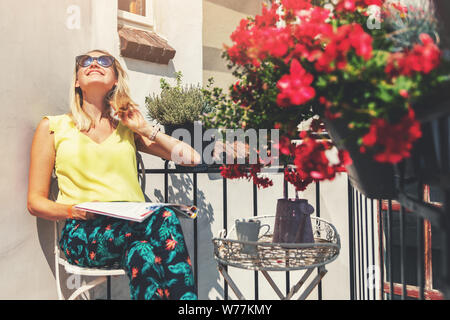 young woman enjoying the sun on romantic balcony with flower boxes Stock Photo