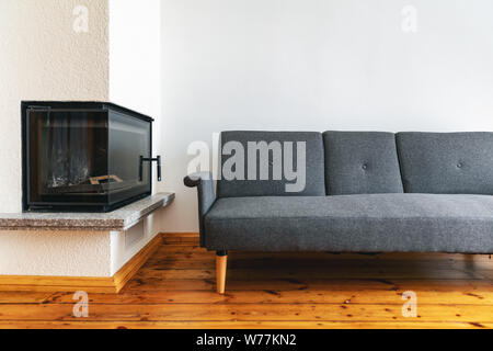 modern bright interior with fireplace and gray sofa on natural wood plank floor Stock Photo