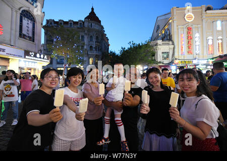 (190805) -- HARBIN, Aug. 5, 2019 (Xinhua) -- Tourists enjoy local ice-cream on the Central Avenue in Harbin, capital of northeast China's Heilongjiang Province, Aug. 1, 2019. Attracted by the coolness in summer, many tourists come to Harbin for vacation. Meanwhile, Harbin is a city of music for the locals who got in touch with European classical music in an earlier time in China. With the cool summer and rich culture, Harbin received 36.23 million tourists and made revenue of 60.7 billion yuan (8.6 billion U.S. dollars) in the summer of 2018. (Xinhua/Wang Jianwei) Stock Photo