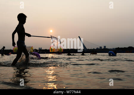 (190805) -- HARBIN, Aug. 5, 2019 (Xinhua) -- A kid plays along the Songhua River in Harbin, capital of northeast China's Heilongjiang Province. Attracted by the coolness in summer, many tourists come to Harbin for vacation. Meanwhile, Harbin is a city of music for the locals who got in touch with European classical music in an earlier time in China. With the cool summer and rich culture, Harbin received 36.23 million tourists and made revenue of 60.7 billion yuan (8.6 billion U.S. dollars) in the summer of 2018. (Xinhua/Wang Jianwei) Stock Photo