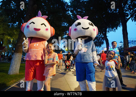 (190805) -- HARBIN, Aug. 5, 2019 (Xinhua) -- Kids pose for photos with the mascots of the city Harbin at a park in Harbin, capital of northeast China's Heilongjiang Province, July 30, 2019. Attracted by the coolness in summer, many tourists come to Harbin for vacation. Meanwhile, Harbin is a city of music for the locals who got in touch with European classical music in an earlier time in China. With the cool summer and rich culture, Harbin received 36.23 million tourists and made revenue of 60.7 billion yuan (8.6 billion U.S. dollars) in the summer of 2018. (Xinhua/Wang Jianwei) Stock Photo