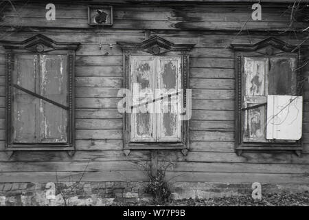 Old abandoned wooden house in black and white. The windows of the house are shuttered. Stock Photo