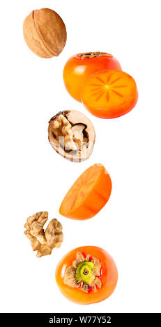 Isolated flying fruit. Falling persimmon with walnut isolated on white background with clipping path as package design element and advertising. depth Stock Photo