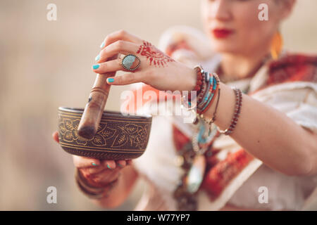 concept. Woman playing a Tibetan bowl. Pregnant woman doing yoga in the field at sunset Stock Photo