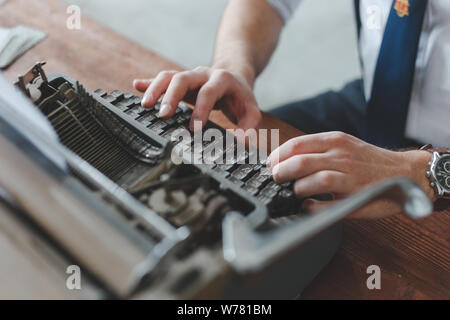 Man working on retro typewriter at desk in parlor room. Stock Photo