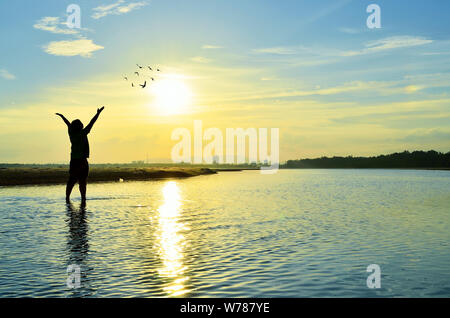 Silhouette of Man Raising His Hands or Open arms when sunset Stock Photo