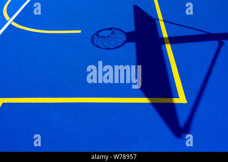 Shadow of a basketball basket on the floor of the court, painted blue and background with lines. Stock Photo