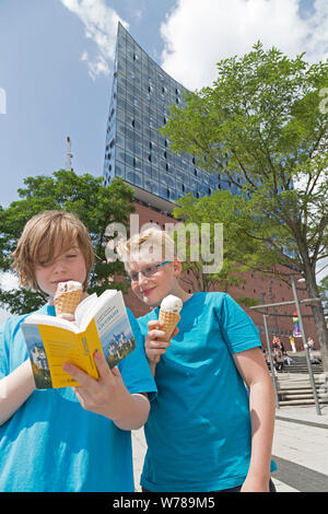 teenagers during language study travel studying their German dictionary in front of Elbe Philharmonic Hall, Hamburg, Germany Stock Photo
