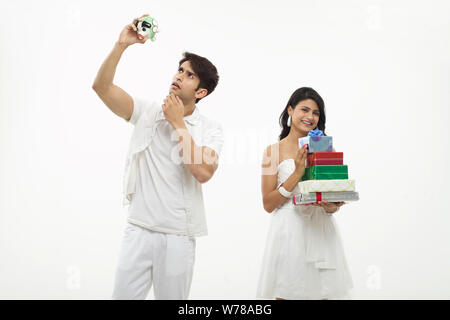 Young man looking piggy bank with her wife holding gift boxes Stock Photo