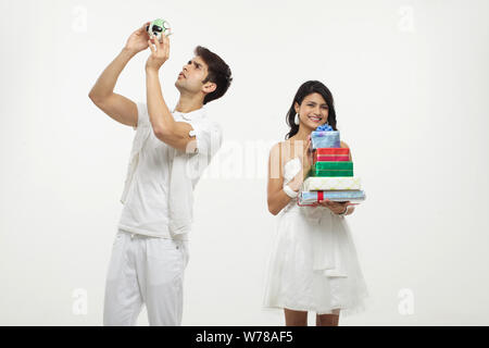 Young man looking piggy bank with her wife holding gift boxes Stock Photo