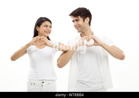 Young couple making heart shape with hands and smiling Stock Photo