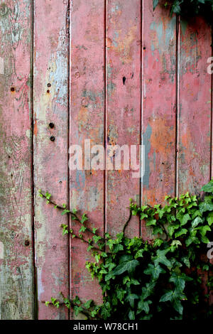 Old wooden garage door with distressed weather-beaten red or pink paint Stock Photo