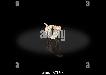 Yellow Gold precious ring snake female with diamonds white and ruby on black background. Good material for design jewelery. Stock Photo