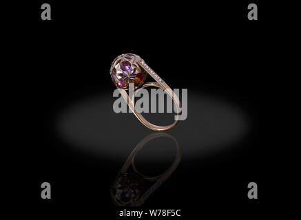 Yello gold precious ball with colored stones ring female with diamonds on black background. Good material for design jewelery. Stock Photo