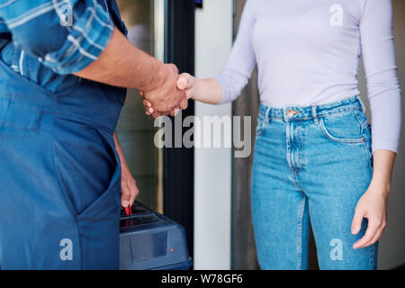 Young female client and repairman shaking hands after mechanic or technical work Stock Photo