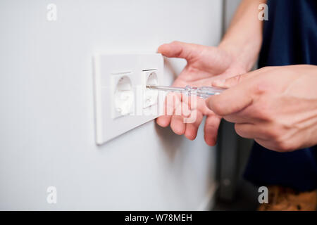 Hands of young professional electrician repairing or checking voltage of socket Stock Photo