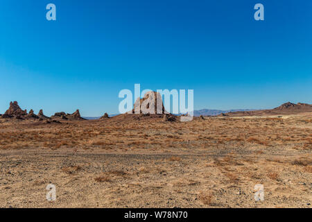 Barren brown desert valley with Pinnacles and rock formations under bright blue sky. Stock Photo