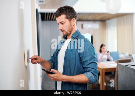 Young serious man installing new smart remote control application Stock Photo