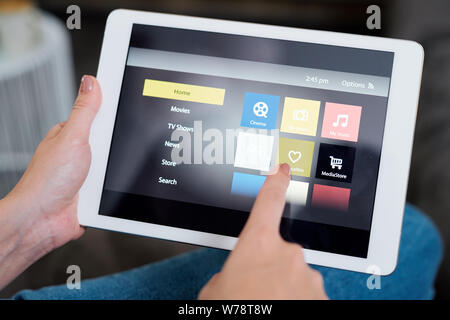 Young female touching heart icon on display while choosing something to watch Stock Photo