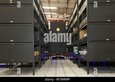 An AGV (Automated Guided Vehicle) robot which is responsible for delivering and sorting out parcels works in the electronics logistics base of Chinese Stock Photo