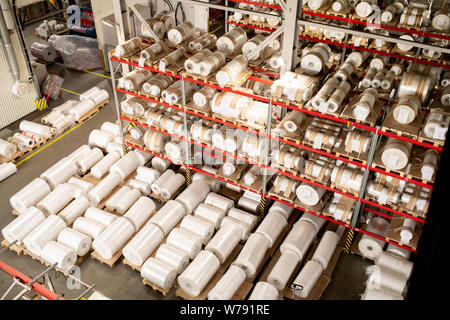 Many rolled polyethylene film units on shelves and racks inside warehouse Stock Photo