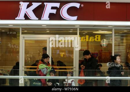 --FILE--Pedestrians walk past a fastfood restaurant of KFC of Yum! Brands in Huaian city, east China's Jiangsu province, 26 February 2017.    It all b Stock Photo