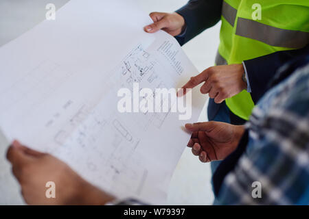 Close-up of a blueprint which two engineers examine. Stock Photo