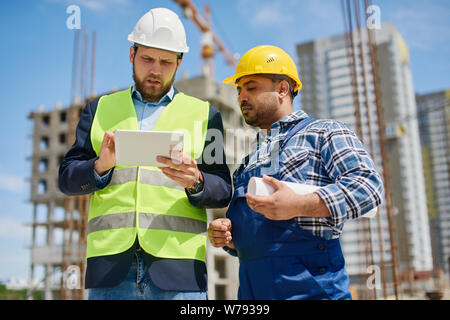 Two engineers discuss work related questions together. Stock Photo