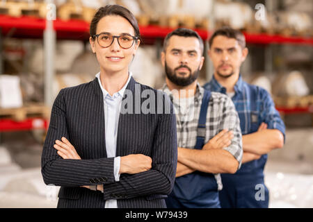 Young confident leader of team standing in front of two factory workers Stock Photo