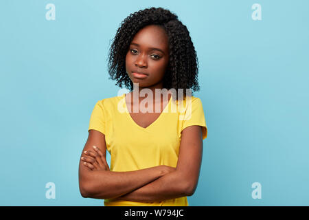 angry sad frustrated young woman dressed casually keeping arms folded, looking at camera with skeptical expression. close up portrait.studio shot. Stock Photo