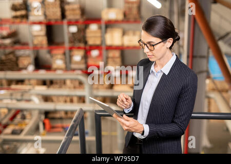 Young expert of industrial plant scrolling in tablet while surfing in the net Stock Photo