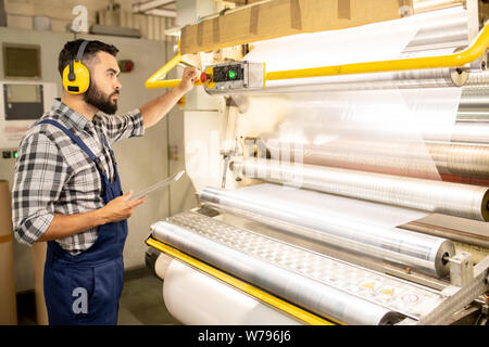 Serious young engineer of chemical production factory taking control of machine Stock Photo