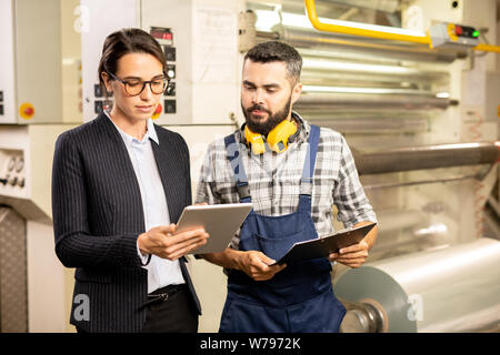 Two young engineers testing new system of quality control in chemical factory Stock Photo