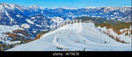 The Alp landscape from the peak of Zwieselalm mount with a view on snowbound cones of Dachstein West mountain range and numerous skiers and snowboarde Stock Photo