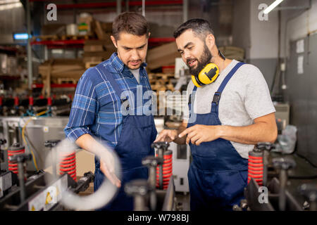 Factory worker explaining his colleague how to use new industrial equipment Stock Photo