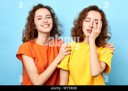 sister trying to calm down her crying sister who has some problems. woman trying to support her favourite sister in difficult situstion . isolated blu Stock Photo