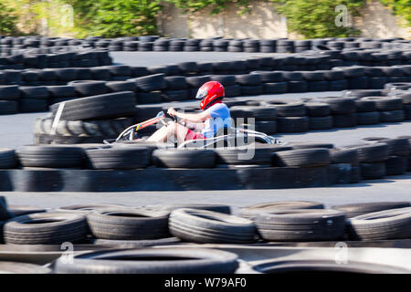 Go-kart driver in red helmet racing between safety tyre barriers Stock Photo