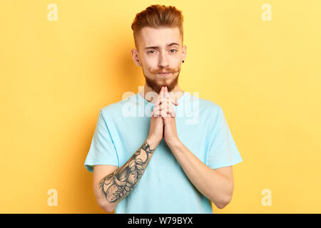 ginger handsome man with funny creative moustache looking at the camera, being puzzled by something, difficult question, man solving a problem. Stock Photo