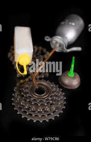 Oiling the bicycle chain with an oil can on the workshop table. Servicing of bicycle parts. Dark background. Stock Photo