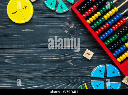 Сolorful math fractions and oranges as a sample on dark wooden background or table. Interesting creative funny math for kids. Education, back to schoo Stock Photo