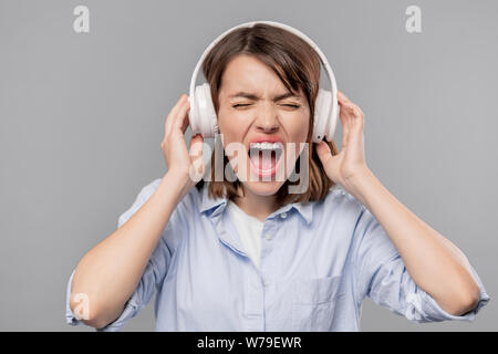 Furious young woman in headphones screaming loudly Stock Photo