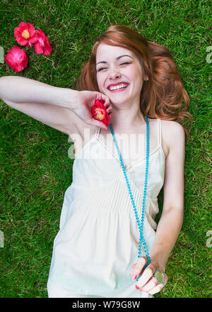 A young woman laying on the grass laughing. Stock Photo