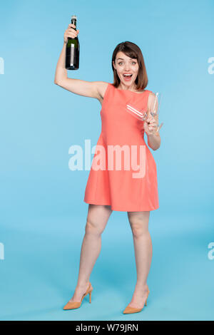Young pin-up female in red dress holding two flutes and bottle of champagne Stock Photo
