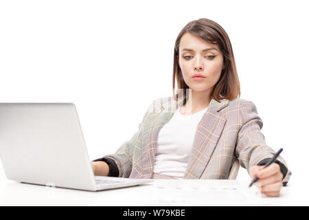 Pensive young woman in formalwear making working notes Stock Photo