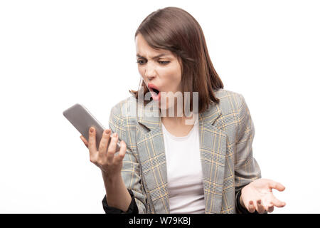 Young furious businesswoman looking at message in smartphone Stock Photo