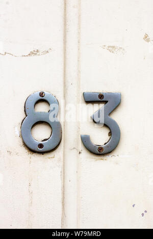 House number 83 on a white wooden front door with vertical boards Stock Photo
